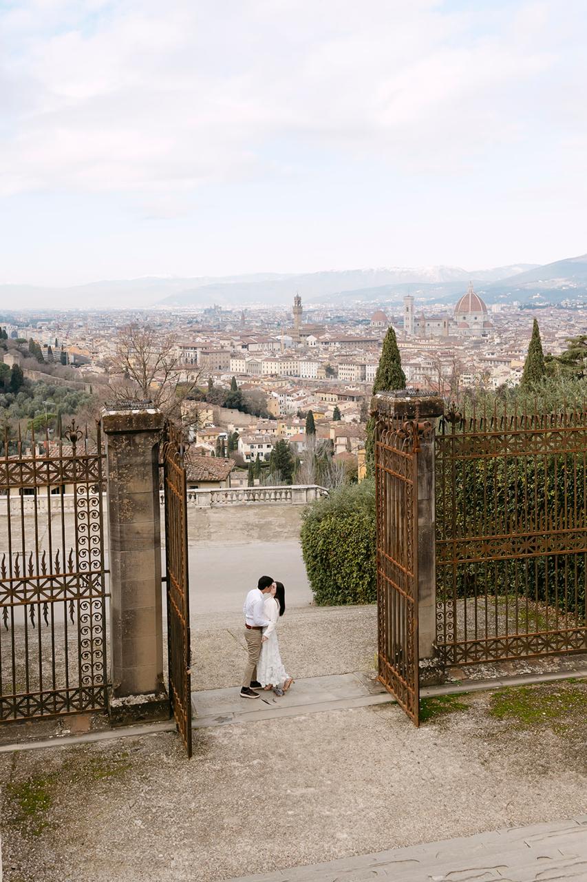 Lívia e André entre os portões com a vista de Florença ao fundo